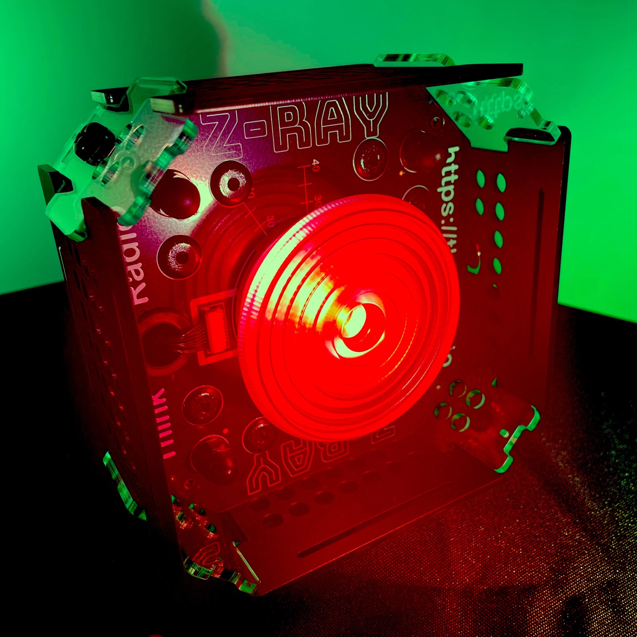 A Z-RAY Wireless DMX light with a Fresnel lens, and illuminated in red, against a greenish background.